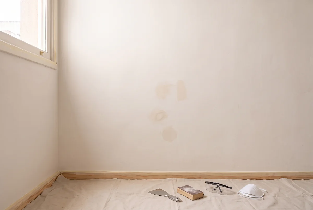 Parede seca preparada, com pequena correção nivelada e piso protegido para a pintura.