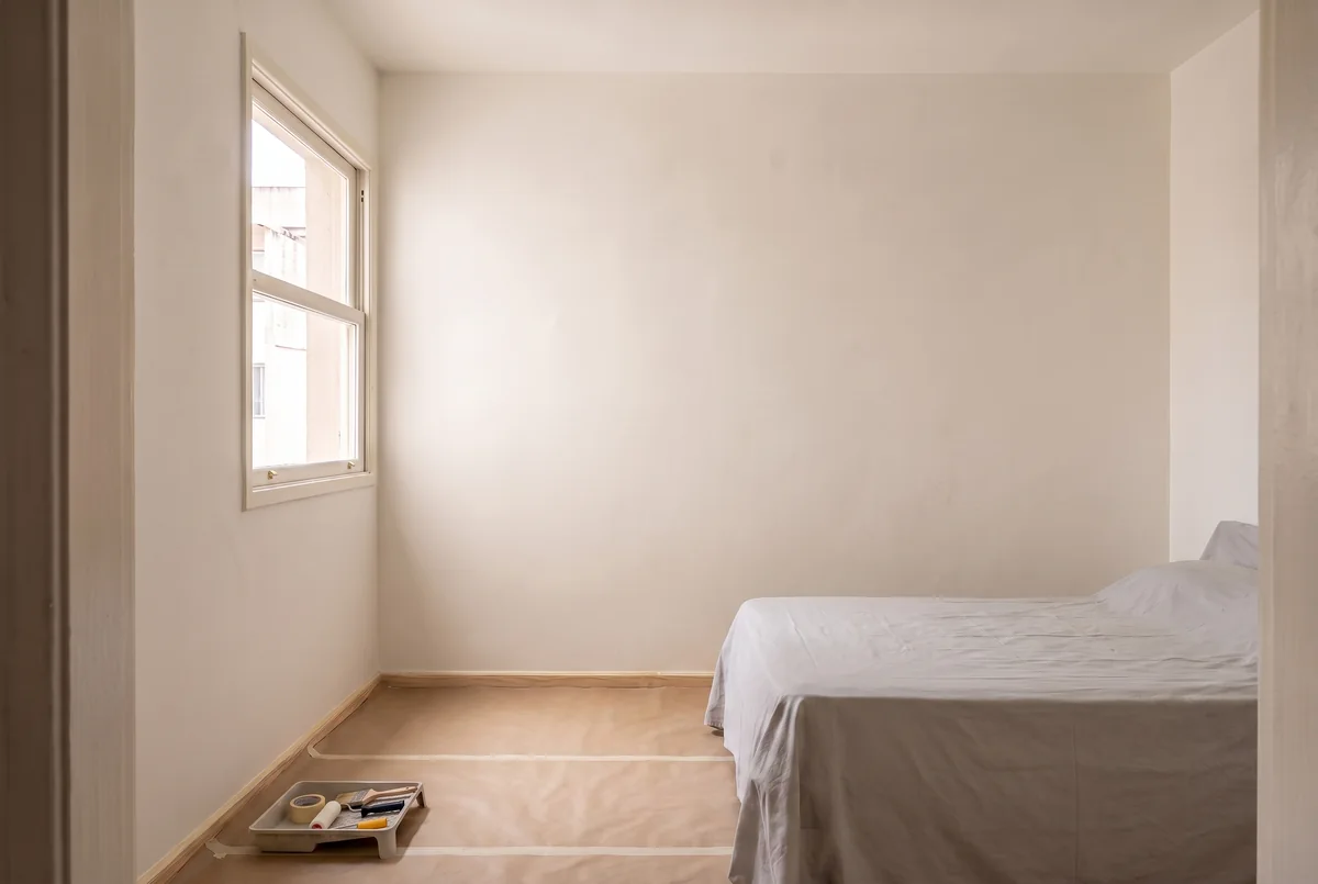Quarto pintado e ventilado, ainda com móveis protegidos enquanto a pintura seca.